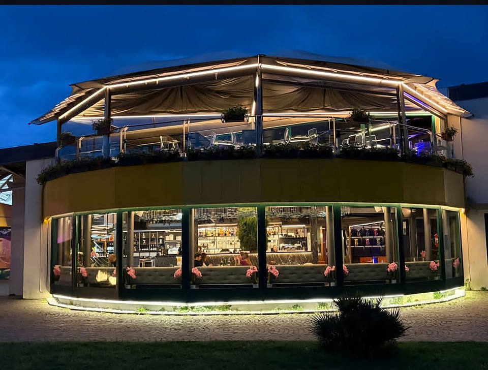 L'esterno di Yotto Sushi illuminato di sera, con la terrazza al piano superiore