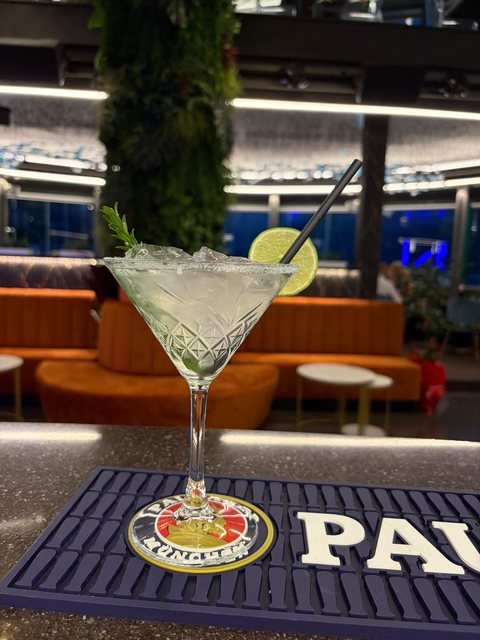 Cocktail servito in coppa Martini, con spicchio di lime e bordo di zucchero, al bancone del cocktail bar
